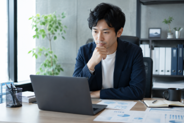 オフィスでパソコンと書類を確認するビジネスマン